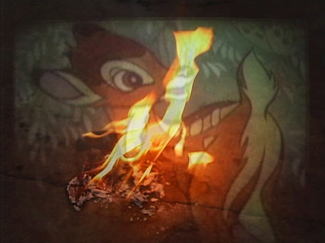 A film still showing a cartoon animation of Bambi the deer with a flame and burn mark either superimposed over the image or burned into the film itself.